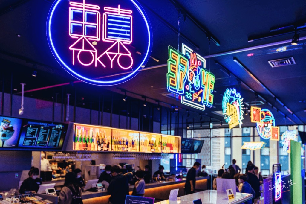 namco TOKYO 的用餐區，牆上是粉紅霓虹圓環招牌